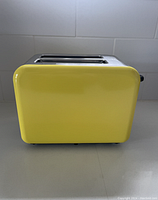 Side view of the yellow enamel toaster showing smooth surface and slot openings on top.