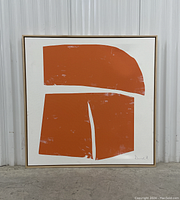 Full view of the orange geometric canvas artwork in blond wood frame leaning against a wall.
