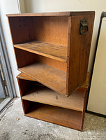 Pair of wooden low bookshelves stacked one on top of the other showing shelves and wear.