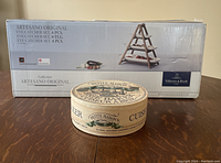 Boxed Villeroy & Boch Artesano Original 3-tiered server set and Petite Maison brie baker in decorative box sitting on table.