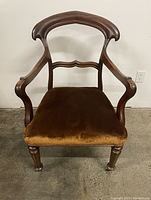 Front view of vintage wooden balloon back armchair with brown velvet seat.