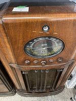 Front view of wooden console radio showing tuning dial, control knobs, and speaker grill.
