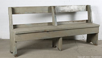Full view of heavy wooden bench with backrest in distressed paint finish, showing general wear and surface marks.