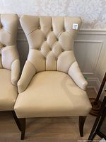 Front view of two cream leather chairs showing diamond tufted backs with crystal buttons