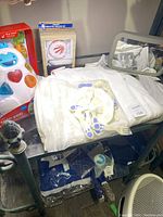 Photo of baby clothing, cutlery set and toy on a black shelf