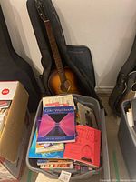 Overview of guitar in soft case and plastic bin of books