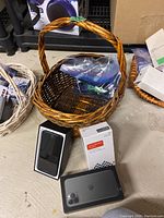 Lot of electronics, basket, and accessories on concrete floor in storage area