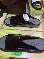 Overview of black leather sandal showing front and side profile on Naot box with detailed stitching visible.