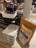 Photo showing white plastic 4-drawer organizer, yellow bubble mailers in wrapped packs, and a white tray containing various smaller items such as tape and labels.