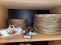 Stacks of dinner and side plates with butter dish and packaged spreader on shelf