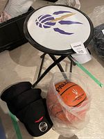 Photo of Raptors folding stool with logo, basketball, and hats arranged on floor