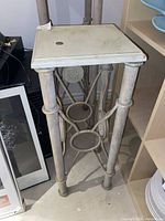 Full view of the metal plant stand showing square top and decorative floral sides