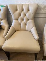 Front view of cream leather chair showing button tufting and armrests