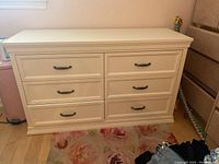 Front view of the white dresser showing six drawers with black handles, closed.