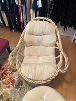 Front view of wicker lounge chair with beige cushioned padding.