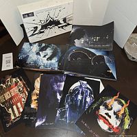 Photo of opened box set showing six Blu-ray discs, booklet, and several art prints/postcards with characters from the trilogy.