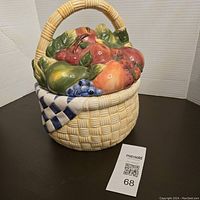 Front and side view of the ceramic cookie jar designed as a fruit basket showing detailed fruit and basket texture.