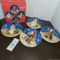 Set of 4 hand painted dessert plates with Christmas snowman and Santa Claus designs, including original box with images of the plates.
