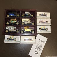 Overall view of 11 diecast mini automobile replicas in wood wall display case with 5 original boxes alongside.