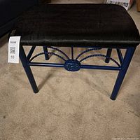 Foot stool bench with blue metal frame and black cushioned seat, showing front with decorative metal work.