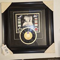 Framed Madonna 45rpm vinyl record titled "Holiday" showing a warped vinyl and a black frame with vintage Madonna imagery.