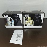 Front and side view of the two boxed mugs showing Star Wars themes and character images of Princess Leia and C-3PO on the packaging.