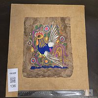 Front view of colorful Mexican folk art rooster painting on textured bark mounted on burlap fabric with ruler for scale.