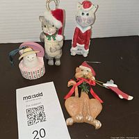Four vintage cat resin ornaments arranged on a flat black surface with auction lot tag visible.