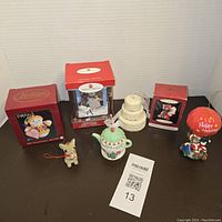 Front view of the seven vintage Christmas collectible ornaments arranged on a black surface including boxed and loose ornaments.