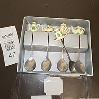 Photo showing all four teaspoons in original packaging with ceramic mini teapots and teacups handles.