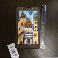 Front view of vintage terracotta wall art tile showing Mediterranean city church design with ruler for size reference.