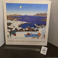 Front view of the vintage Thomas McKnight Mykonos Rooftops wall plaque showing the full 18x18 inch artwork with a ruler for scale.