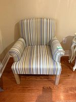 Front view of striped arm chair showing multi-color vertical striped fabric upholstery and wooden legs.