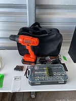 Full view of cordless drill with battery, charger, carrying case, socket and bit set, and additional bits arranged on table.