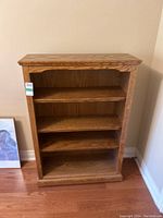 Front-facing view of the wood bookcase showing three shelves and the medium wood grain finish