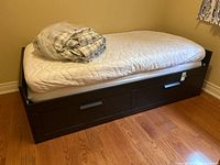 Front view of IKEA daybed with foam mattress and bedding folded on top