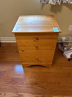 Front view of the pine filing cabinet showing all three drawers and natural wood finish.