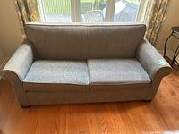Front view of grey fabric sofa with two large seat cushions and wood feet