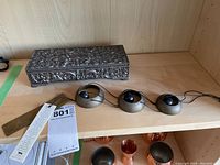Photo showing the detailed heavy silver tone jewelry box with embossed floral and scroll design and the set of three brass temple bells wind chimes connected by cords.