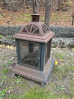 Front-side angled view showing rusted metal firepit with mesh screens and door.
