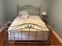 Front view of the queen metal bed with bedding and pillows.