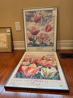 Two framed Skagit Valley Tulip Festival 1990 and 1991 posters displayed on the floor with one leaning against the wall.
