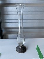 Tall clear glass vase with a flared rim and sterling silver weighted base shown full height and overall profile.