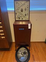 Overall shot of sheet music cabinet topped with lock and key display and oval photo frame leaning in front