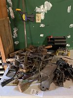 General overview of table showing bench anvil, assorted hand tools and clamps piled together