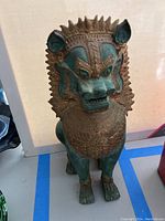 Full front view of the standing gilt bronze guardian lion on a white background