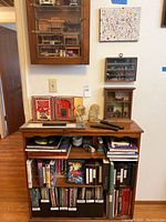 Full view of bookshelf loaded with books, binders, DVDs, and decor items including miniatures and bookends.