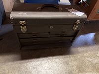 Closed Kennedy tool box on the floor showing front side with multiple drawers and carrying handle on top