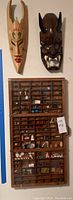 Overview showing display case with assorted miniatures mounted below two masks