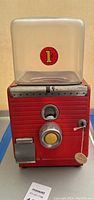 Overall front view of the red 1949 Northwestern gumball machine with clear globe and coin slot.